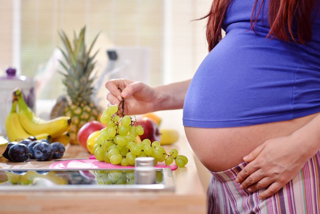 pragnant woman holding grapes